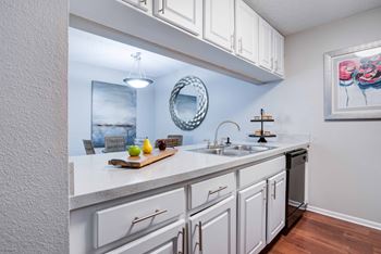 A kitchen with white cabinets and a wooden cutting board on the counter